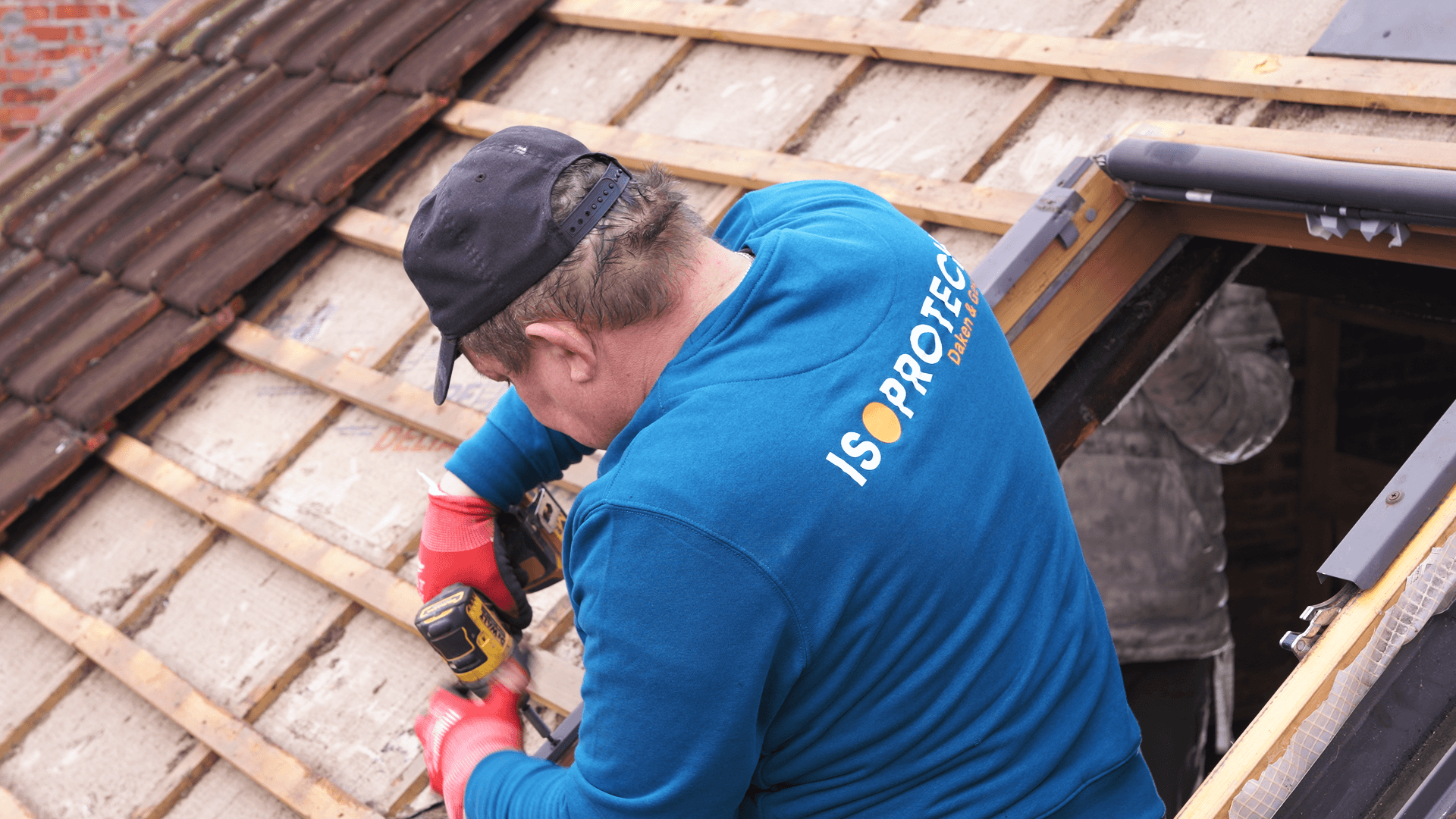 ISOPROTECH vakman aan het werk op hellend dak — blauwe sweater